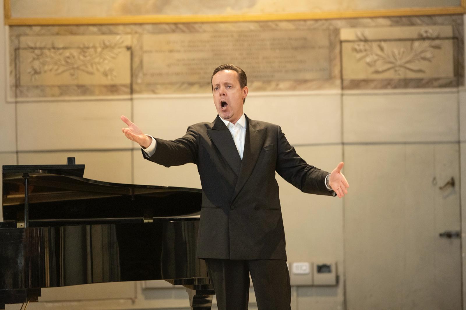 Un tenore appassionato canta al pianoforte durante un concerto di musica da camera a Firenze.